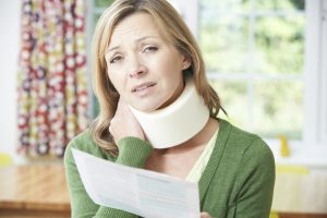 woman with a neck brace holding a paper that looks to be in discomfort